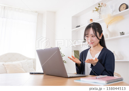 オンライン会議でパソコンに向かって話す20代女性 138044513
