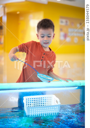 Happy boy scooping fish with a small net Happy boy scooping fish with a small net 138044579