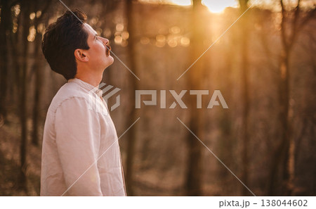 Hopeful Man Looking Up at Sunset in Spring Forest Hopeful Man Looking Up at Sunset in Spring Forest 138044602