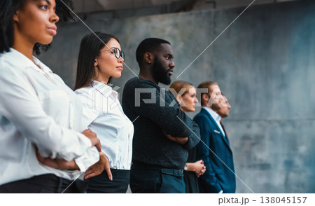 Group of people standing together with arms crossed in a modern setting during a formal event at a workplace Group of people standing together with arms crossed in a modern setting during a formal event at a workplace 138045157