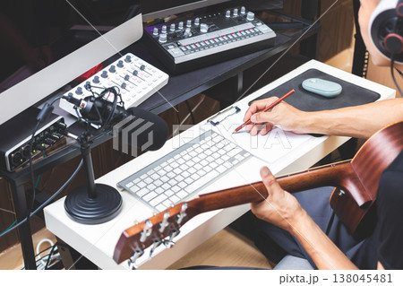 male musician writing a hit song by acoustic guitar in home studio 138045481