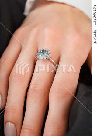 Beautiful female hand with gold ring with diamonds and emerald on gray background Beautiful female hand with gold ring with diamonds and emerald on gray background 138046158