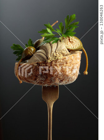 Bread with liver pate, capers, and fresh parsley on a fork. 138046263