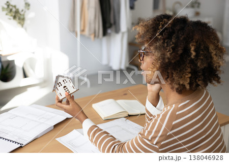 female architect or realtor holds mock up of house in her hands, talks on phone with client. female architect or realtor holds mock up of house in her hands, talks on phone with client. 138046928