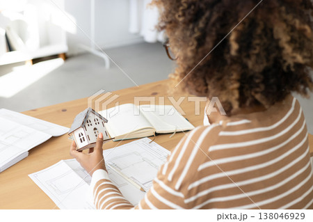 female architect or realtor holds mock up of house in her hands, talks on phone with client. 138046929
