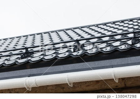Close-up view of glossy metal roof tiles and white gutter Close-up view of glossy metal roof tiles and white gutter 138047298