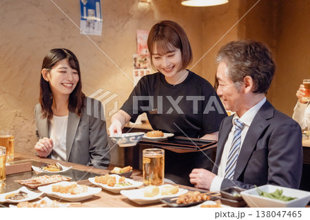 居酒屋で料理を提供する女性スタッフ 138047465