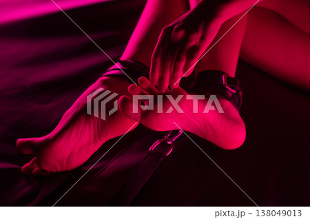 Women's legs in leather shackles. BDSM fetish. 138049013