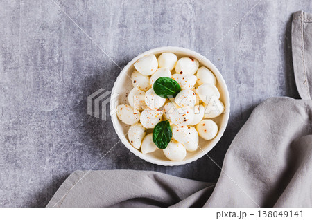 Close up of mozzarella cheese in small balls in a bowl on the table top view Close up of mozzarella cheese in small balls in a bowl on the table top view 138049141