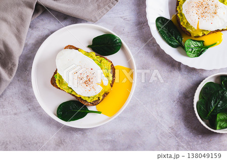 Rye bread with guacamole and poached egg on a plate on the table top view Rye bread with guacamole and poached egg on a plate on the table top view 138049159