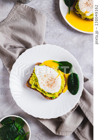 Avocado sandwich with poached egg and spinach on a plate top and vertical view Avocado sandwich with poached egg and spinach on a plate top and vertical view 138049162