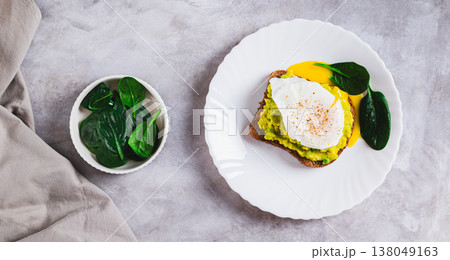 Avocado sandwich with poached egg and spinach on a plate top view web banner 138049163