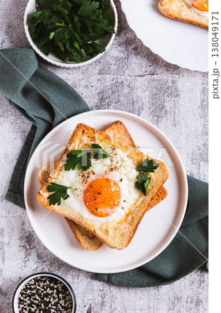 Baked toast with egg and parsley on a plate on the table top and vertical view Baked toast with egg and parsley on a plate on the table top and vertical view 138049171