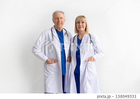 Portrait of mature male and female doctors wearing white coats and scrubs 138049331