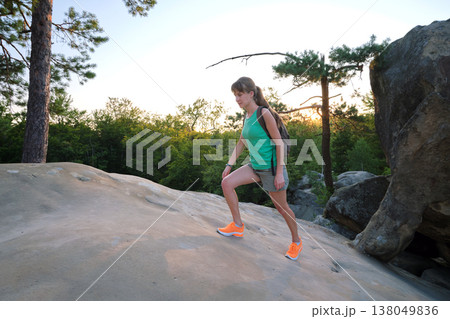 Young woman hiking alone on mountain footpath. Female hiker enjoying view of evening nature on wilderness trail. Active way of life concept Young woman hiking alone on mountain footpath. Female hiker enjoying view of evening nature on wilderness trail. Active way of life concept 138049836