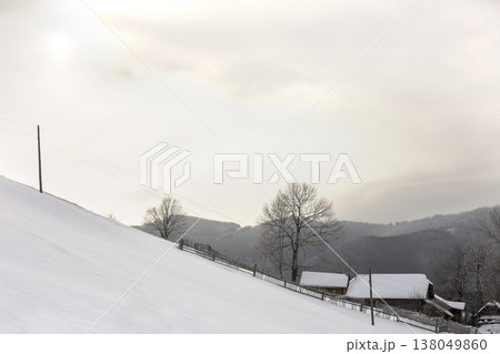 Winter mountain landscape. Snowy slope, wooden fence and house on woody mountain ridge and bright blue sky copy space background. Happy New Year and Merry Christmas card. Winter mountain landscape. Snowy slope, wooden fence and house on woody mountain ridge and bright blue sky copy space background. Happy New Year and Merry Christmas card. 138049860