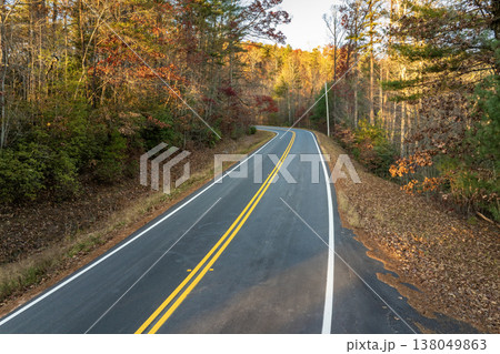 Winding forest road in Tennessee Appalachians during fall. Car traveling through mountain woods under glowing autumn leaves Winding forest road in Tennessee Appalachians during fall. Car traveling through mountain woods under glowing autumn leaves 138049863