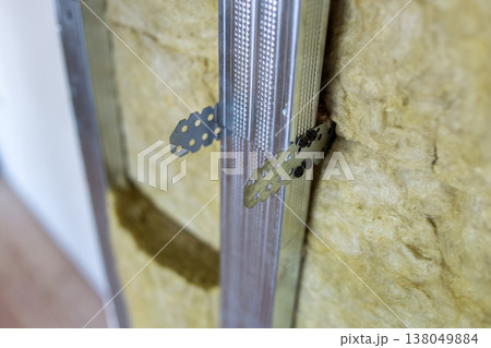 Wall of a room under renovation with mineral rock wool insulation and metal frame prepared for drywall plates. 138049884