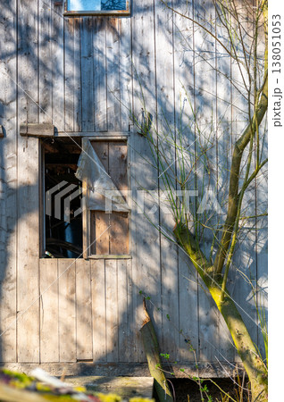 Old wooden wall with small open window and torn curtain, rustic rural scene, concept of privacy, curiosity and mystery, abandoned place and simple countryside life Old wooden wall with small open window and torn curtain, rustic rural scene, concept of privacy, curiosity and mystery, abandoned place and simple countryside life 138051053