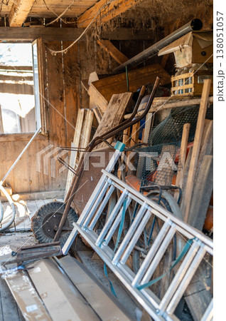 Messy old workshop interior with tools ladder and wheelbarrow, rustic workspace, concept of manual work, repair, maintenance and authentic rural lifestyle 138051057