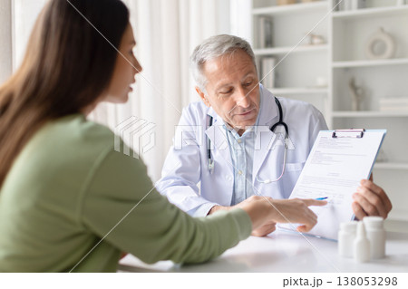 Senior male doctor explaining medical document and treatment plan to female patient Senior male doctor explaining medical document and treatment plan to female patient 138053298