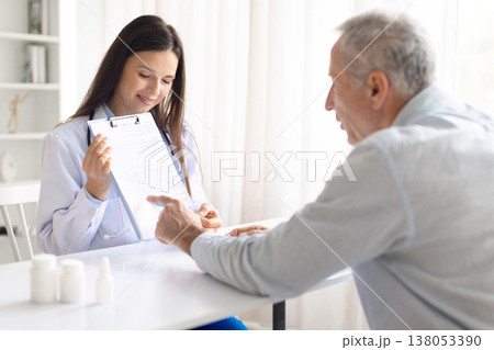 Female doctor reviewing medical document with senior patient in clinic 138053390