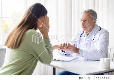 Senior male doctor comforting emotional female patient during medical consultation Senior male doctor comforting emotional female patient during medical consultation 138053511