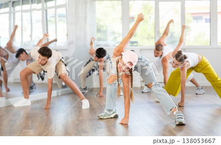 Team of teenagers rehearsing modern dances in dance hall Team of teenagers rehearsing modern dances in dance hall 138053667