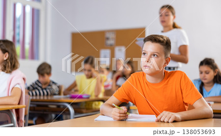 Portrait of schoolboy who writing exercises at lesson in primary school Portrait of schoolboy who writing exercises at lesson in primary school 138053693