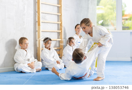 Children athletes in pair conduct training battle in oriental fighting technique Children athletes in pair conduct training battle in oriental fighting technique 138053746