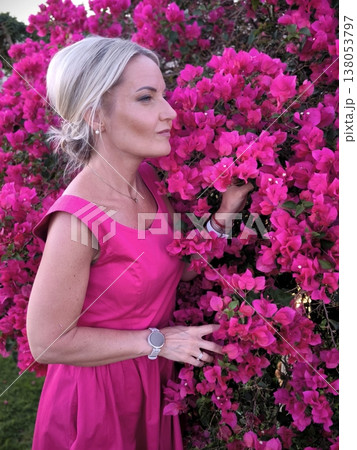 Woman in pink dress admires bright bougainvillea flowers 138053797