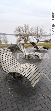 wooden benches in the form of sun loungers on the site overlooking the lake 138053805