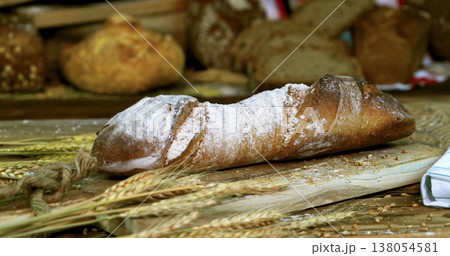 Freshly baked bread on a wooden board with wheat and other types of bread in a bakery setting 138054581