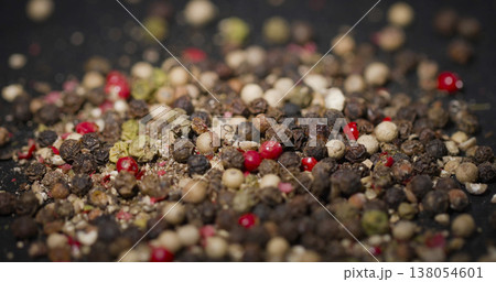 Mix of different peppercorns placed on a dark surface for culinary use in cooking and seasoning dishes at home or restaurants 138054601