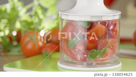 Chopping tomatoes and herbs in a kitchen with fresh ingredients and tools for meal preparation 138054625