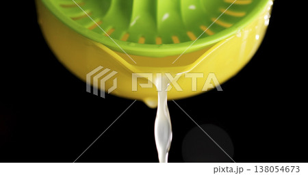 Juice dripping from a green lemon squeezer in a black background during a kitchen operation Juice dripping from a green lemon squeezer in a black background during a kitchen operation 138054673