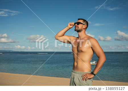 Man wearing sunglasses looks at the ocean under the sun Man wearing sunglasses looks at the ocean under the sun 138055127