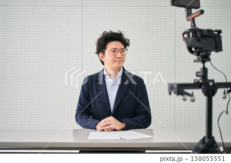 撮影スタジオでカメラに向かってニュース原稿を読み上げるアナウンサー 撮影スタジオでカメラに向かってニュース原稿を読み上げるアナウンサー 138055551