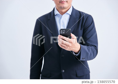 白背景で正面からスマートフォンを持つ顔無しのスーツ姿の男性 白背景で正面からスマートフォンを持つ顔無しのスーツ姿の男性 138055570