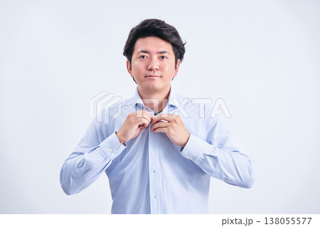 白背景の前でカメラ目線でワイシャツを着替える30代の日本人の1人の男性 138055577