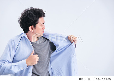白背景の前で身だしなみや汗の匂いを気にしてワイシャツを着替える30代の男性 138055580