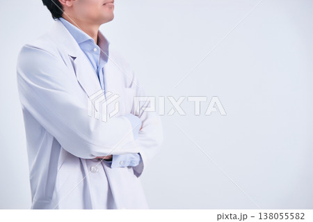 白背景の前で横から撮影した腕組みをする顔無しの白衣姿の30代の男性の医者 白背景の前で横から撮影した腕組みをする顔無しの白衣姿の30代の男性の医者 138055582