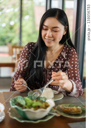 woman eating with food in restaurant woman eating with food in restaurant 138056783