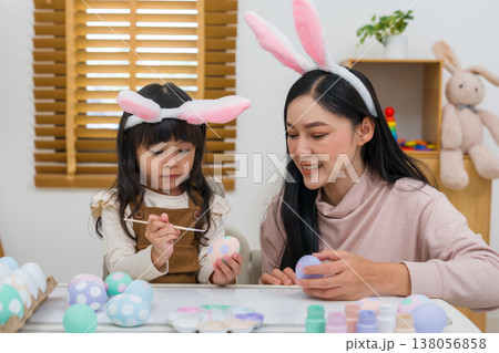 mother and preschool child girl wearing bunny ears painting and decorating egg together at home on easter day. happy family holiday activity concept mother and preschool child girl wearing bunny ears painting and decorating egg together at home on easter day. happy family holiday activity concept 138056858