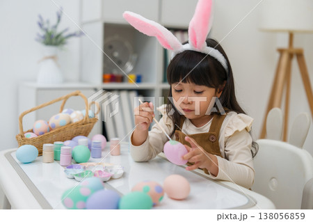 preschool child girl wearing bunny ears painting and decorating colorful egg at home on easter day 138056859