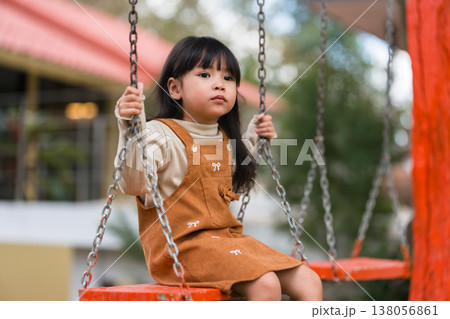 child girl playing on wooden swing at playground child girl playing on wooden swing at playground 138056861