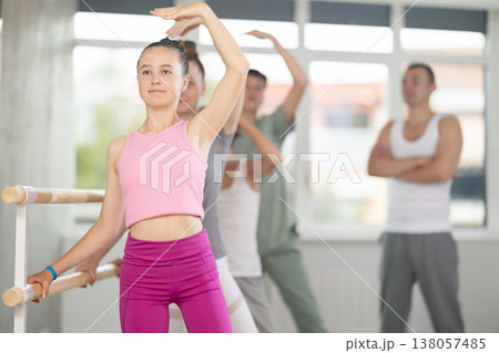 Girl during group class perform third position under male teacher guidance. 138057485