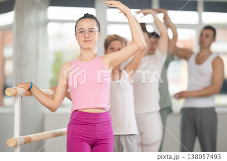 Girl during group class perform third position under male teacher guidance. Girl during group class perform third position under male teacher guidance. 138057493