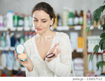 Woman purchases household chemicals in store and chooses eye shadow pallet 138057512