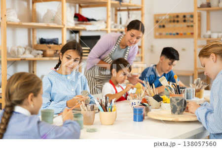 Children painting ceramics with a teacher Children painting ceramics with a teacher 138057560